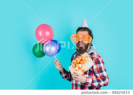 What to buy. event manager with gift box. brutal male on party. funny man in birthday hat. happy holiday celebration. party goer going crazy. having fun with balloons. prepare for anniversary 98825653