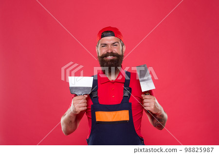 Professional plasterer. Skillful plasterer. Successful renovation. Repair success. Bearded man worker with plastering tools. Plasterer hipster builder in cap red background. Interior designer Professional plasterer. Skillful plasterer. Successful renovation. Repair success. Bearded man worker with plastering tools. Plasterer hipster builder in cap red background. Interior designer 98825987
