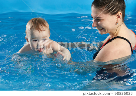 Little baby learning to swim in pool with teacher Little baby learning to swim in pool with teacher 98826023