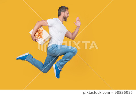 Active man running to deliver present box. Delivery boy in midair. Express delivery service. Fast delivery Active man running to deliver present box. Delivery boy in midair. Express delivery service. Fast delivery 98826055