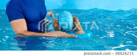 Male trainer teaching preschool boy how to swim in indoor pool with pool flutter board Male trainer teaching preschool boy how to swim in indoor pool with pool flutter board 98826215