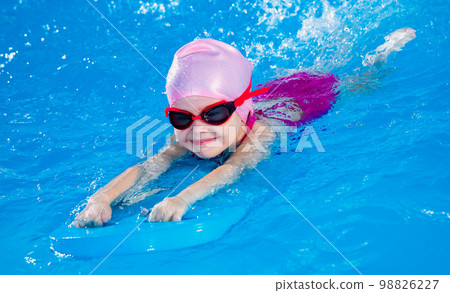 Preschool cute girl learning to swim in indoor pool with flutter board Preschool cute girl learning to swim in indoor pool with flutter board 98826227