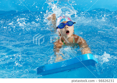 Little girl learning to swim in indoor pool with pool board 98826231