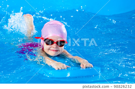 Preschool cute girl learning to swim in indoor pool with flutter board Preschool cute girl learning to swim in indoor pool with flutter board 98826232