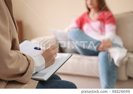 Professional psychotherapist and patient in office, focus on hands with notebook 98826699