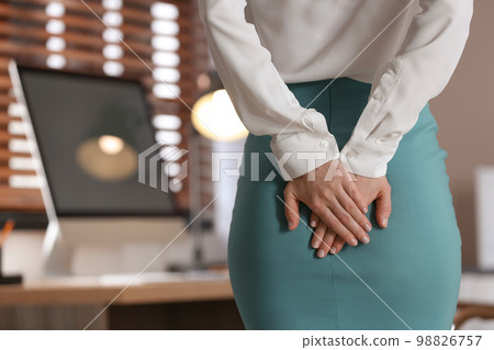 Young woman suffering from hemorrhoid in office, closeup 98826757