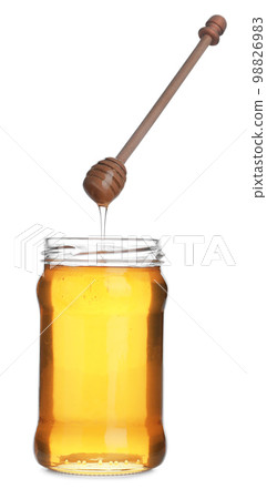 Honey dripping from wooden dipper into jar isolated on white Honey dripping from wooden dipper into jar isolated on white 98826983