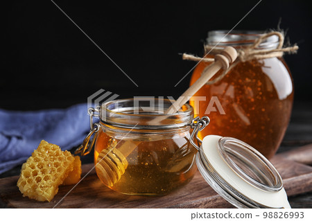 Jar of sweet honey on wooden board 98826993