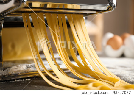 Pasta maker machine with dough on grey table, closeup 98827027