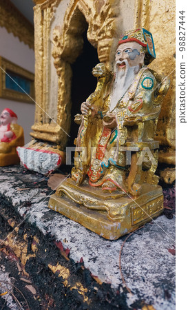 Vertical shot of an old golden statue of Confucius in a Khmer shrine in Kampot Cambodia 98827444