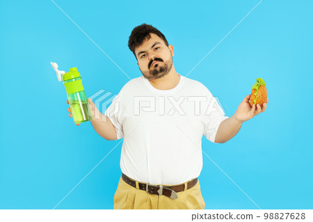 Concept of weight problems, young fat man on blue background Concept of weight problems, young fat man on blue background 98827628