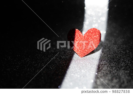 Red heart on a dark background with a narrow band of light. Romantic postcard. Valentine's Day is the feast of lovers. 98827838