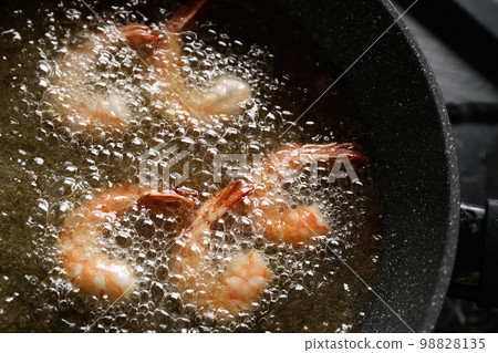 Cooking delicious shrimps in hot oil, closeup Cooking delicious shrimps in hot oil, closeup 98828135