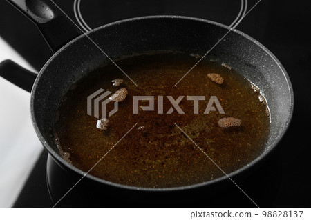 Used cooking oil in frying pan on stove 98828137