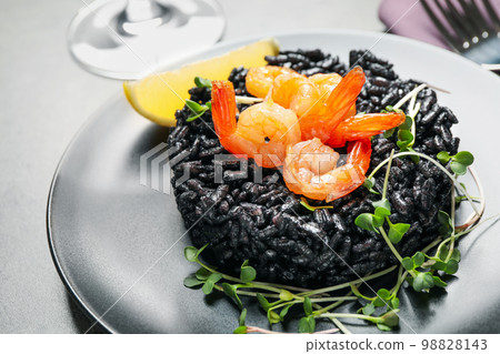 Delicious black risotto with shrimps on table, closeup Delicious black risotto with shrimps on table, closeup 98828143