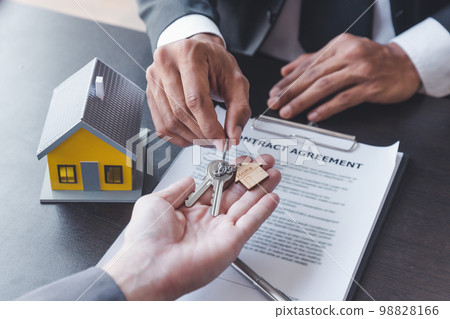 Home sales,home rental and real estate concept.Hands of estate agent giving keys to the Customer after sign the document while explain about the terms of the home purchase or rental agreement 98828166