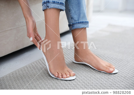 Woman fitting orthopedic insole at home, closeup Woman fitting orthopedic insole at home, closeup 98828208