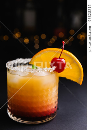 Fresh alcoholic Tequila Sunrise cocktail on black table 98828215