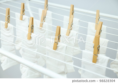 White socks hanging on drying rack on light background 98828304