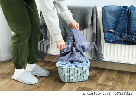 Woman putting clothes on radiator, home routines Woman putting clothes on radiator, home routines 98828328