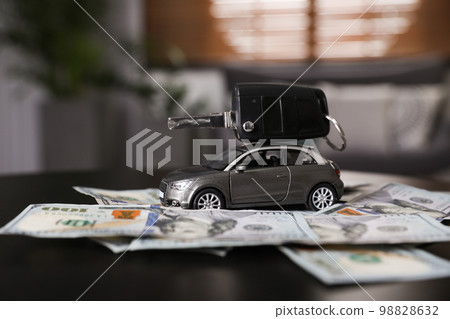 Miniature automobile model, key and money on table indoors. Car buying Miniature automobile model, key and money on table indoors. Car buying 98828632