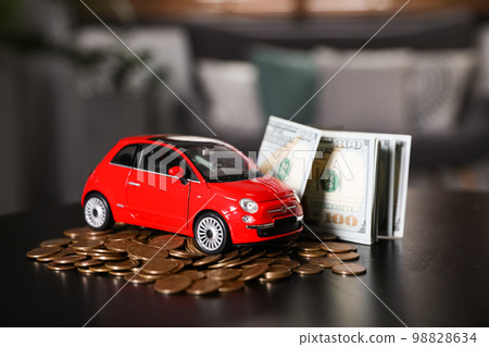 Miniature automobile model and money on table indoors. Car buying Miniature automobile model and money on table indoors. Car buying 98828634