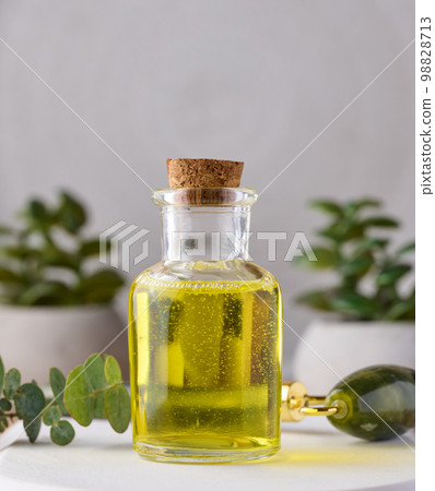 Transparent glass bottle with yellow oil and eucalyptus branch, cosmetic product 98828713