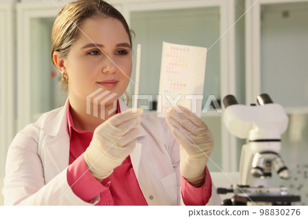 A young woman is a scientist looking at a lakmus strip 98830276