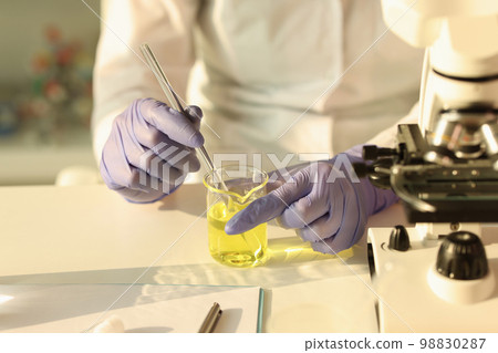 The scientist hands with a pipette in a yellow liquid The scientist hands with a pipette in a yellow liquid 98830287