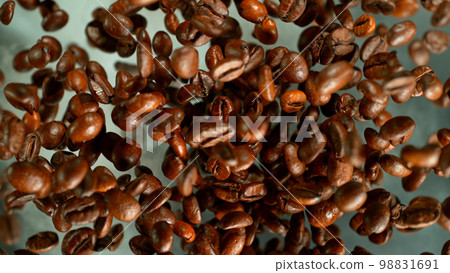 Freeze motion shot of rotating coffee beans, brown gradient background Freeze motion shot of rotating coffee beans, brown gradient background 98831691