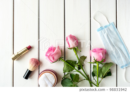 Top view arrangement with make-up, roses, medical mask and copy-space on white wooden background Top view arrangement with make-up, roses, medical mask and copy-space on white wooden background 98831942