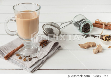 A glass of hot Indian masala tea brewed with aromatic spices and milk 98831943