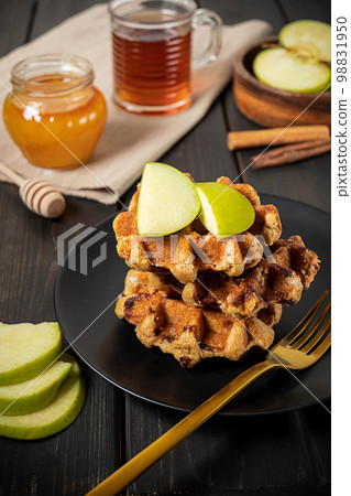 Traditional Belgian waffles with sliced green apple, honey and a cup of tea Traditional Belgian waffles with sliced green apple, honey and a cup of tea 98831950