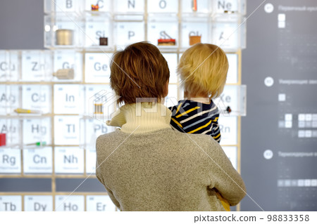 Little boy and woman looking an exposition in a scientific museum. Child is interested in chemistry. Education and entertainment for children. Activities for family with kids. 98833358