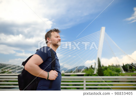 Portrait of middle age man on the background of cable stayed bridge. Millennium bridge is above Moraca river in Podgorica, Montenegro. Portrait of middle age man on the background of cable stayed bridge. Millennium bridge is above Moraca river in Podgorica, Montenegro. 98833405