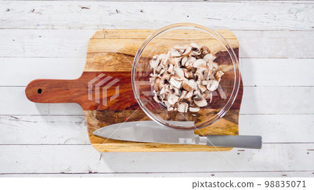Flat lay. Cutting organic Bella mushrooms on a wood cutting board. 98835071