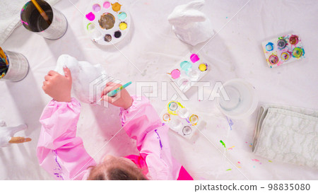 Flat lay. Little girl painting paper mache figurine at homeschooling art class. 98835080