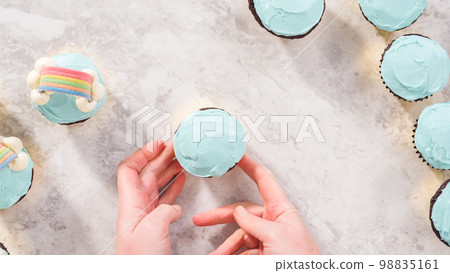 Flat lay. Step by step. Decorating chocolate cupcakes with buttercream frosting and rainbow candy. 98835161