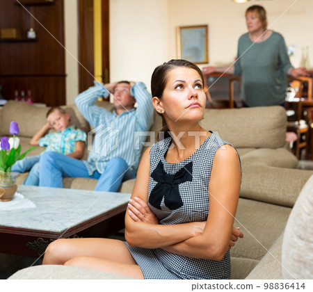 Upset woman sitting during quarrelling between family on background Upset woman sitting during quarrelling between family on background 98836414