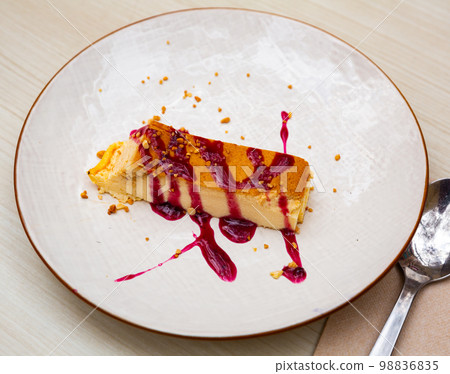 Slice of delicious cake with cheese mousse with blueberry topping on plate. Spanish dessert tarta de queso con arandano 98836835