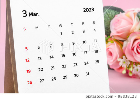 Close up the March 2023 Monthly desk calendar with dried rose on pink background. Close up the March 2023 Monthly desk calendar with dried rose on pink background. 98838128