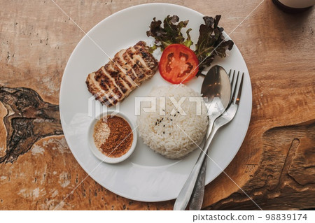 Baked chicken with white rice served on the table. Baked chicken with white rice served on the table. 98839174