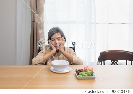 Lonely senior asian woman bored with food. Lonely senior asian woman bored with food. 98840426