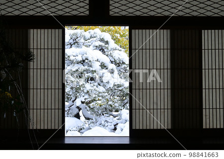 The snow garden of Iwakura Myoman-ji Temple in Kyoto seen through a snow-covered shoji screen 98841663