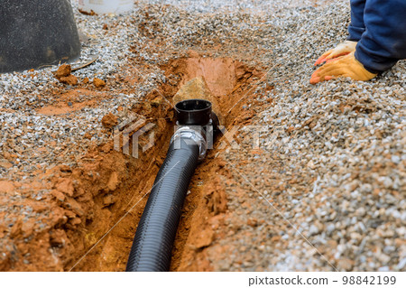 Putting drainage pipe for rain water on gravel sidewalk of car parking lot where parking lot 98842199