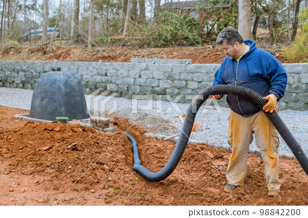 Putting down drainage pipes for rainwater on parking lot which is covered with gravel has driveway Putting down drainage pipes for rainwater on parking lot which is covered with gravel has driveway 98842200
