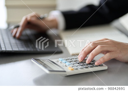 The hand of a male tax accountant who calculates with a calculator The hand of a male tax accountant who calculates with a calculator 98842691