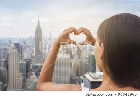 New York Tourist doing heart shape with hands gesture at NYC skyline view from rooftop. View from behind, USA Travel vacation destination 98842968