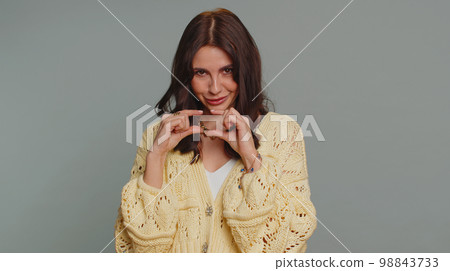 Woman showing a little bit gesture with sceptic smile, showing minimum sign, measuring small size 98843733