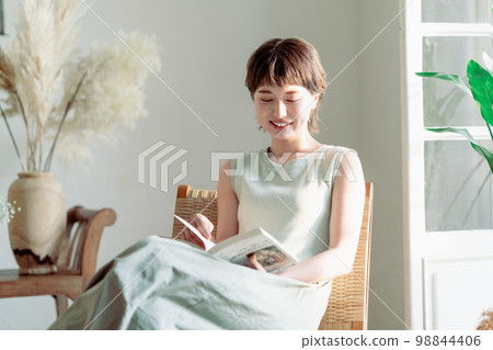 一個穿著裙子在窗邊看書的年輕女人 98844406